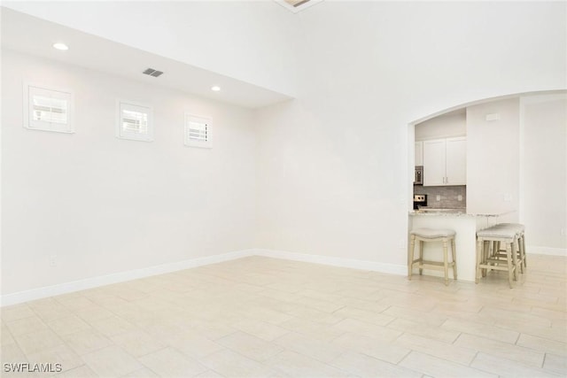 unfurnished room with arched walkways, recessed lighting, visible vents, and baseboards