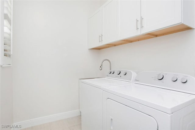 clothes washing area with cabinet space, baseboards, and washer and dryer