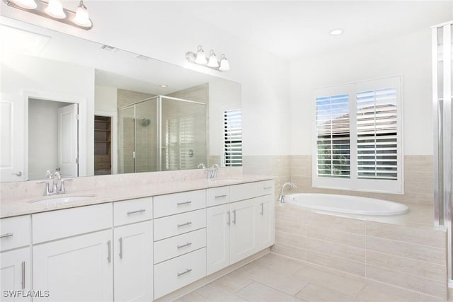 bathroom featuring a garden tub, double vanity, a stall shower, and a sink