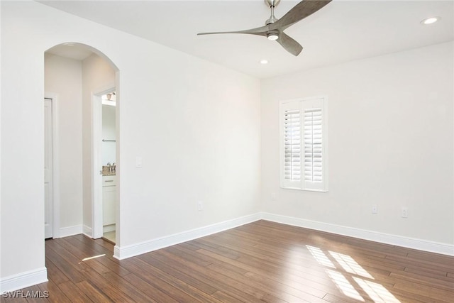 unfurnished room featuring arched walkways, recessed lighting, dark wood-type flooring, ceiling fan, and baseboards