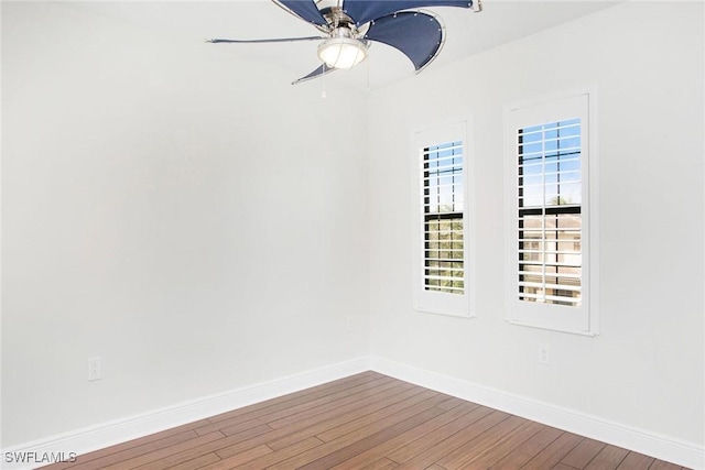 spare room with wood finished floors, a ceiling fan, and baseboards