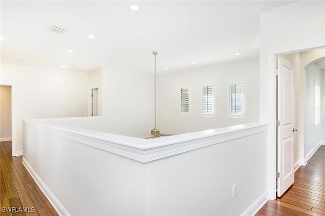 hall featuring recessed lighting, visible vents, arched walkways, and wood finished floors