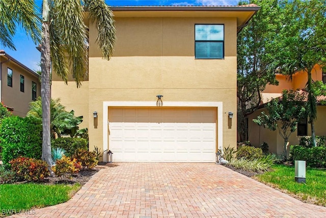 view of front of home with a garage, decorative driveway, and stucco siding