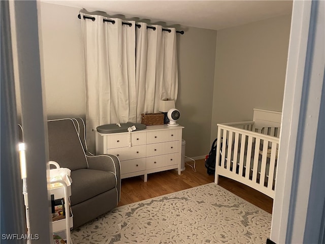 bedroom featuring wood-type flooring and a crib