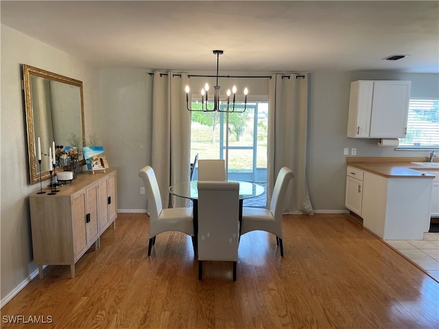 dining room featuring light hardwood / wood-style floors, sink, and an inviting chandelier