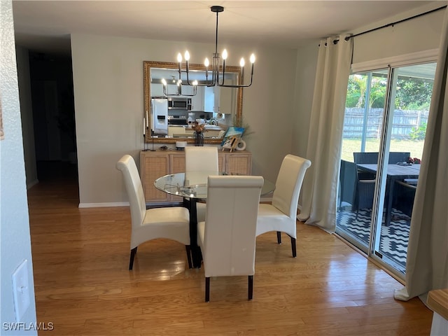 dining area with light hardwood / wood-style flooring and a notable chandelier