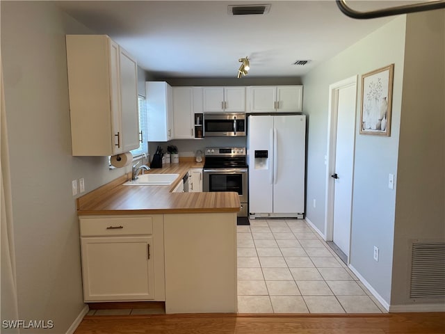 kitchen with white cabinets, stainless steel appliances, sink, and light tile patterned floors