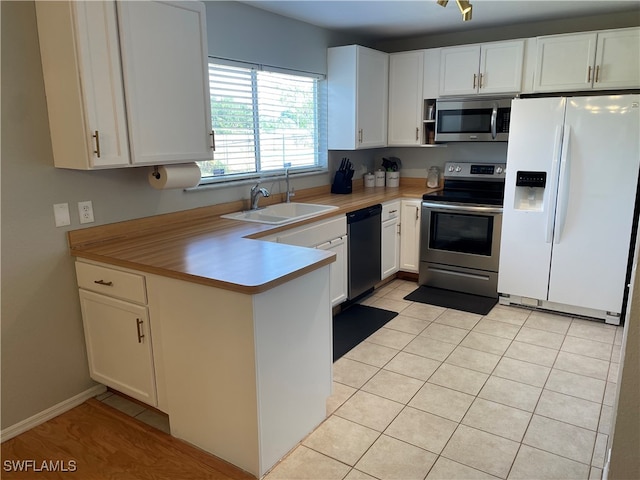 kitchen with light tile patterned floors, white cabinetry, sink, and appliances with stainless steel finishes