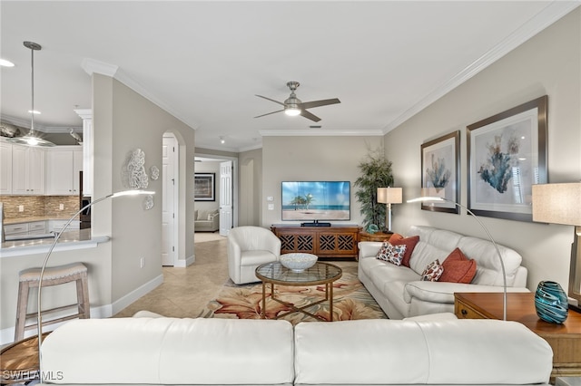 tiled living room with ceiling fan and crown molding