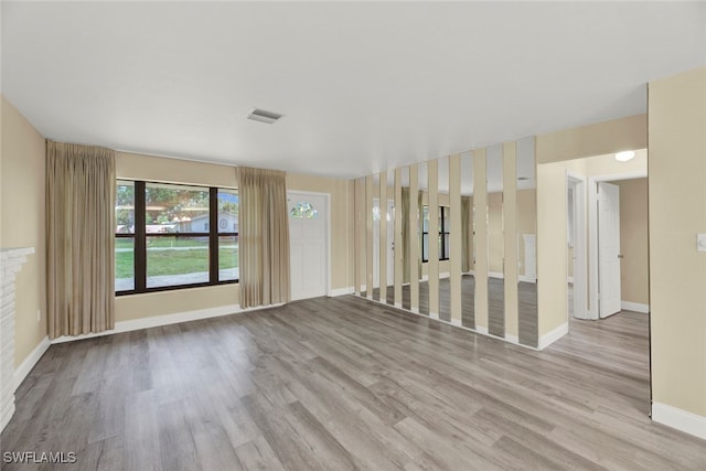 spare room with a brick fireplace and light hardwood / wood-style floors