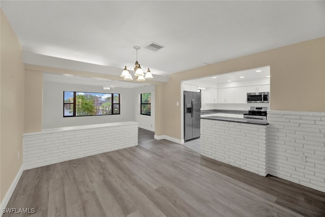 kitchen with white cabinets, kitchen peninsula, appliances with stainless steel finishes, and light hardwood / wood-style floors