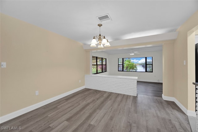 unfurnished living room featuring ceiling fan with notable chandelier and light hardwood / wood-style flooring