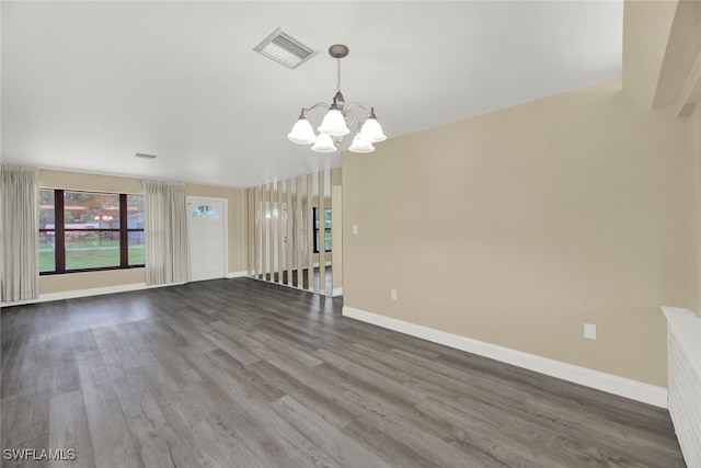 spare room featuring wood-type flooring and a notable chandelier