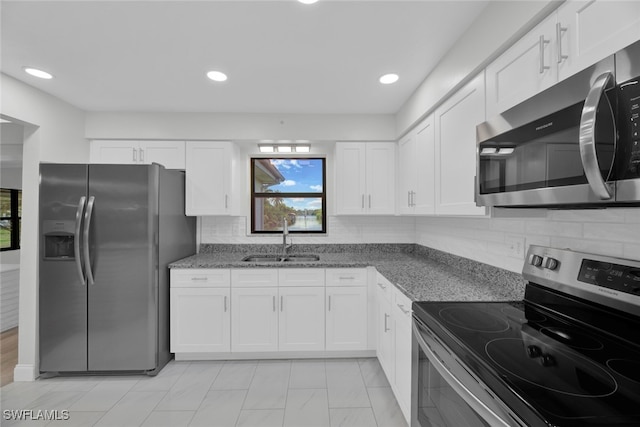 kitchen with dark stone countertops, white cabinetry, sink, and appliances with stainless steel finishes