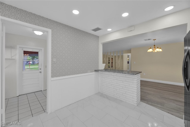 kitchen featuring kitchen peninsula, light hardwood / wood-style flooring, hanging light fixtures, and a chandelier