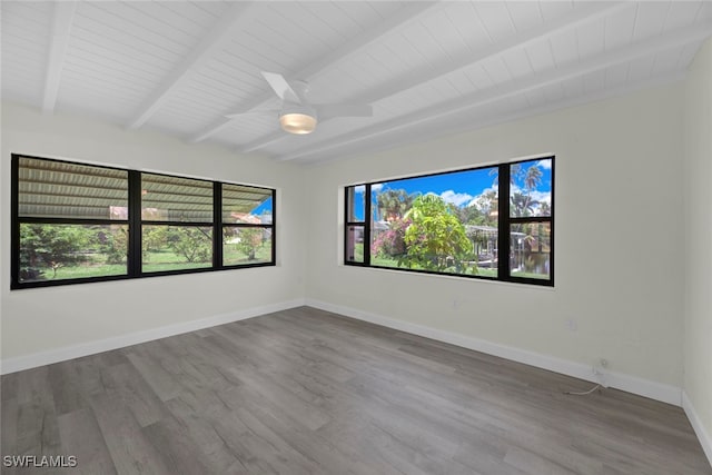 empty room featuring beamed ceiling, hardwood / wood-style flooring, ceiling fan, and wooden ceiling