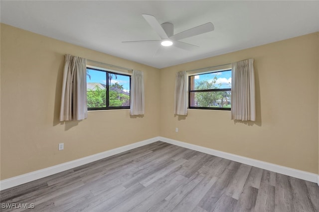 spare room with a wealth of natural light, ceiling fan, and light hardwood / wood-style flooring