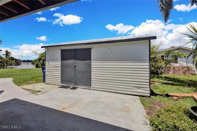 view of outbuilding with a water view and a lawn