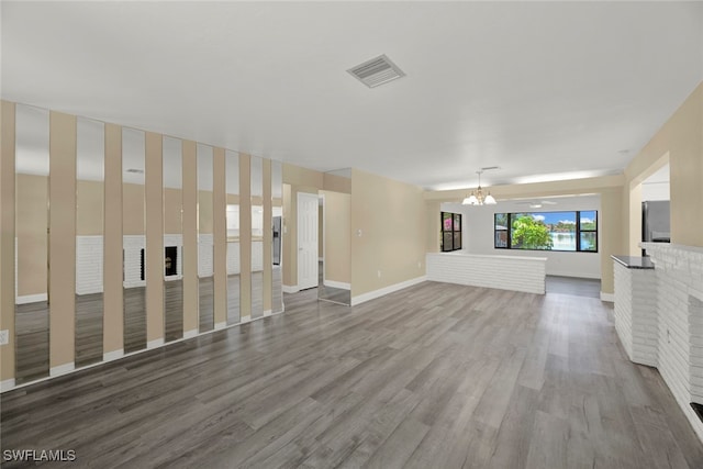 unfurnished living room with an inviting chandelier, wood-type flooring, and a fireplace