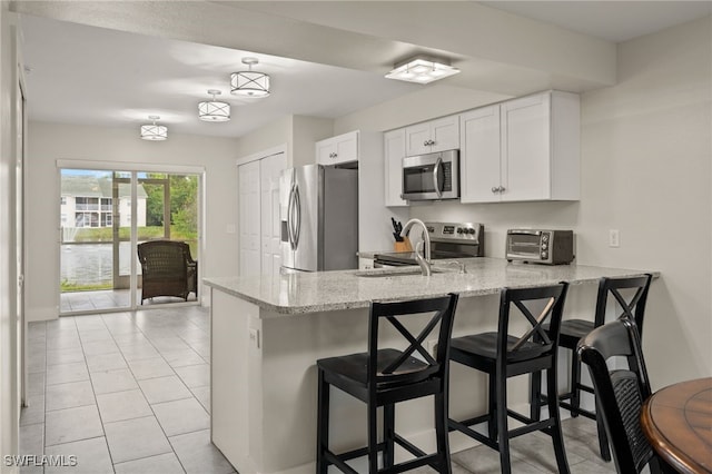 kitchen with white cabinetry, a kitchen bar, appliances with stainless steel finishes, and kitchen peninsula