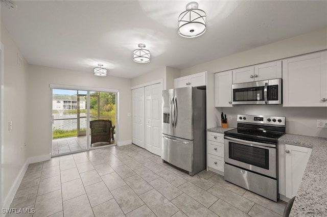 kitchen featuring white cabinets, light stone countertops, light tile patterned flooring, and appliances with stainless steel finishes