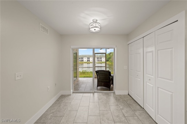 doorway with a water view and light tile patterned flooring