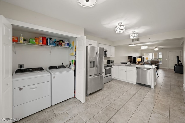 interior space with stainless steel appliances, white cabinets, sink, and washing machine and clothes dryer