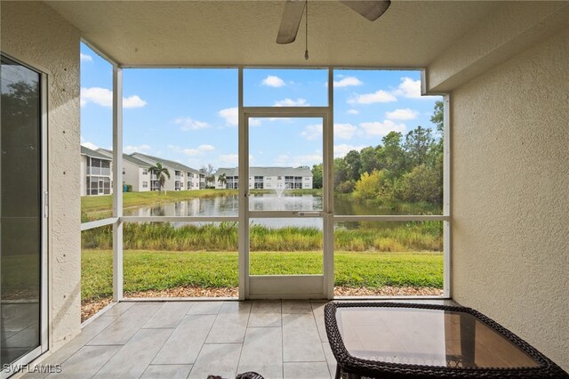 unfurnished sunroom with a water view and ceiling fan