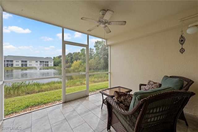 sunroom with a wealth of natural light, a water view, and ceiling fan