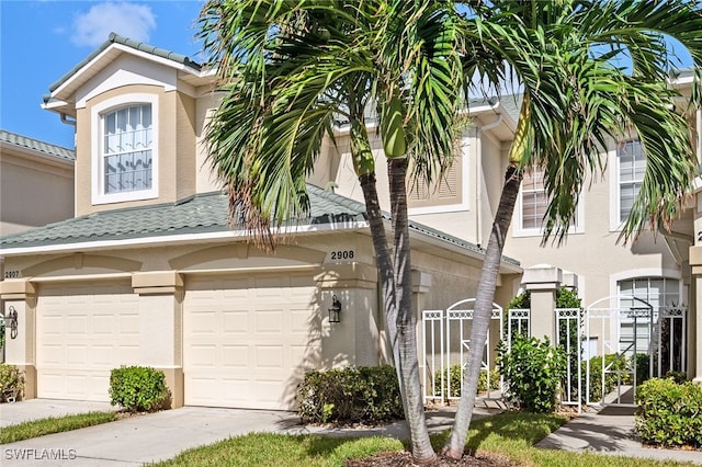 view of front of home featuring a gate, driveway, an attached garage, and stucco siding