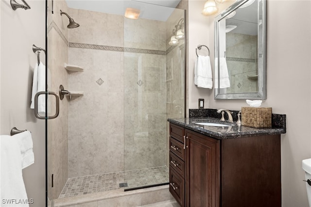 bathroom with a shower with shower door, vanity, and toilet