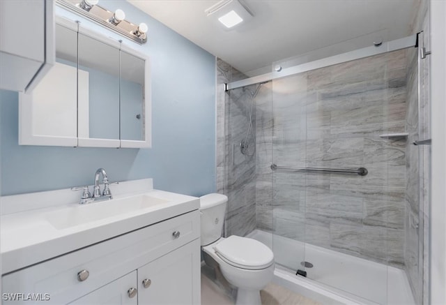 bathroom with toilet, vanity, and a shower with door