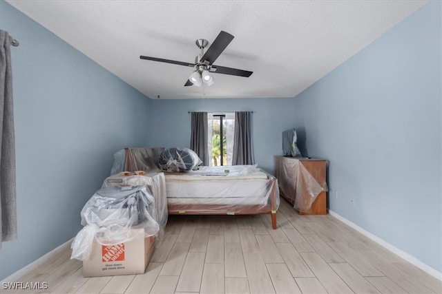 bedroom featuring light hardwood / wood-style floors, ceiling fan, and a textured ceiling