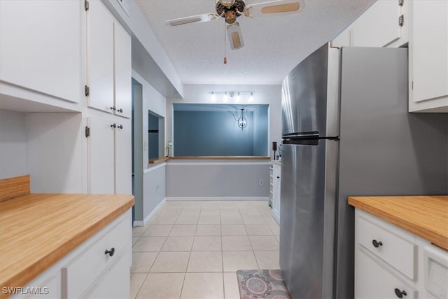 kitchen featuring light tile patterned flooring, stainless steel fridge, a textured ceiling, white cabinets, and ceiling fan