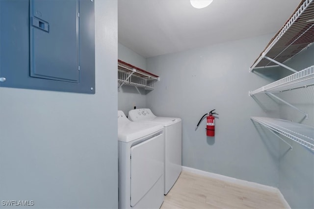 washroom featuring electric panel, light wood-type flooring, and independent washer and dryer