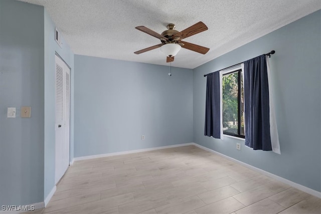 empty room with ceiling fan and a textured ceiling