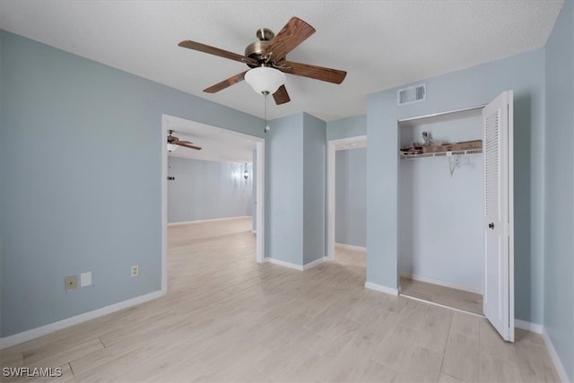 unfurnished bedroom featuring a closet, light wood-type flooring, a textured ceiling, and ceiling fan