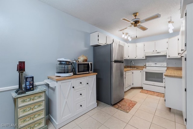 kitchen with stainless steel appliances, light tile patterned flooring, white cabinets, and a textured ceiling