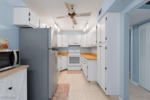 kitchen featuring sink, appliances with stainless steel finishes, a textured ceiling, light tile patterned floors, and white cabinets