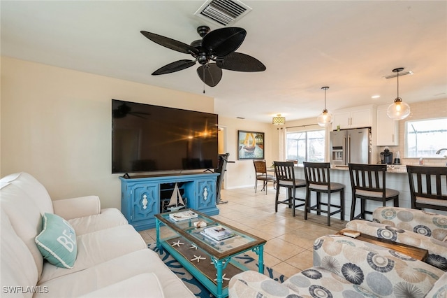 tiled living room with a wealth of natural light and ceiling fan