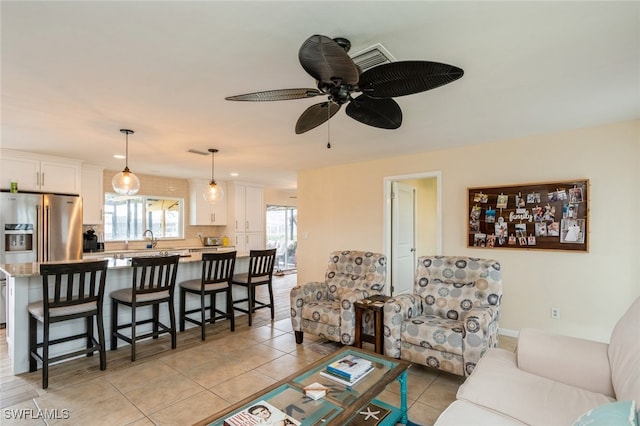 living room featuring ceiling fan, sink, and light tile patterned flooring