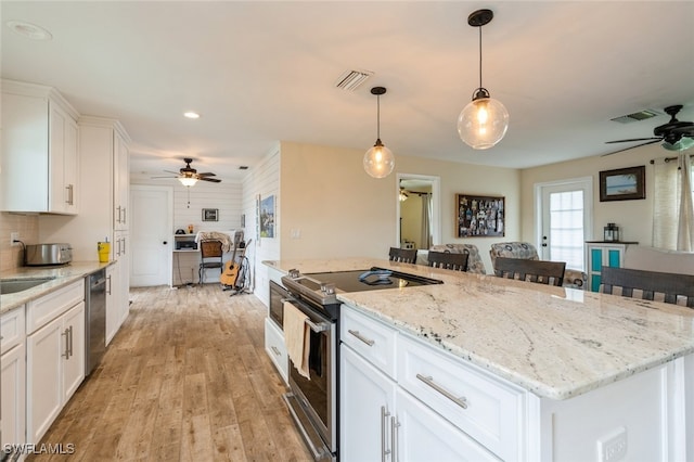 kitchen featuring stainless steel appliances, a kitchen island, white cabinetry, pendant lighting, and light hardwood / wood-style floors