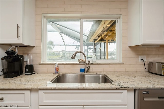 kitchen with tasteful backsplash, sink, light stone counters, and white cabinets