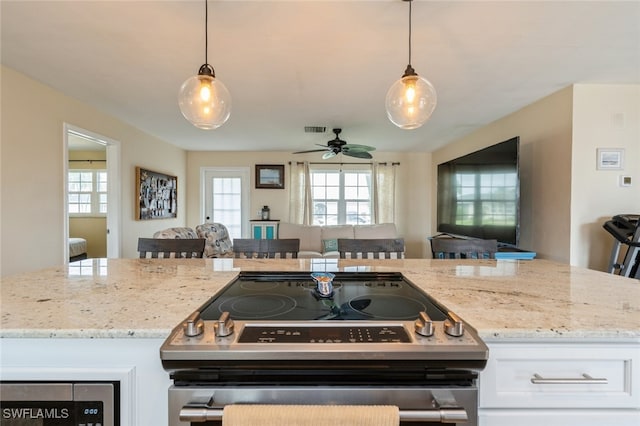 kitchen with white cabinetry, a kitchen bar, hanging light fixtures, and stainless steel range oven