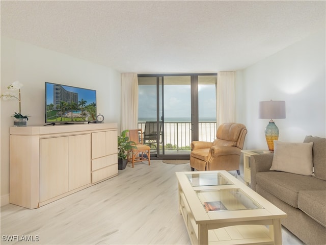 living room featuring a textured ceiling, light hardwood / wood-style floors, and a wall of windows