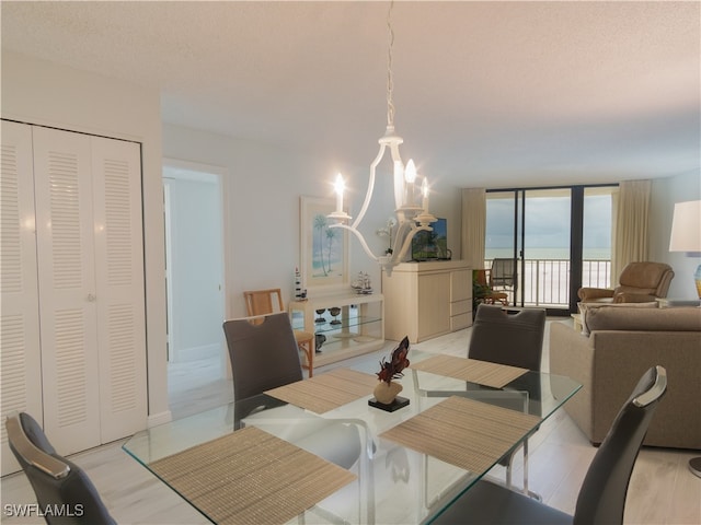 dining room with a textured ceiling, light hardwood / wood-style floors, a notable chandelier, and a water view