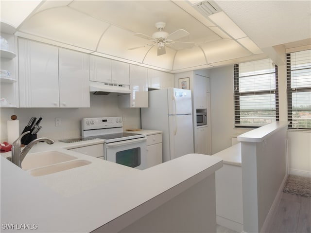 kitchen with white appliances, white cabinetry, sink, and hardwood / wood-style flooring