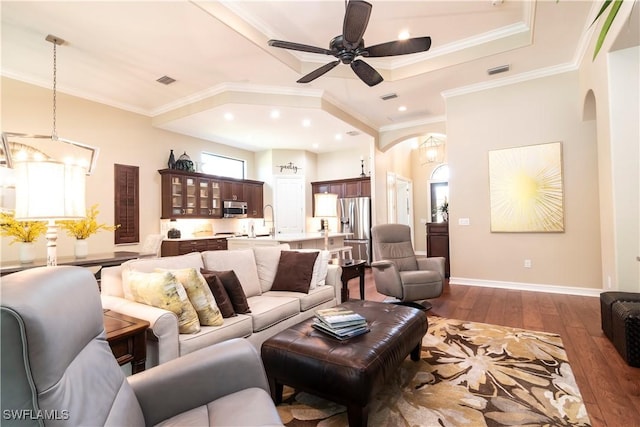 living room with ceiling fan with notable chandelier, dark hardwood / wood-style flooring, and ornamental molding