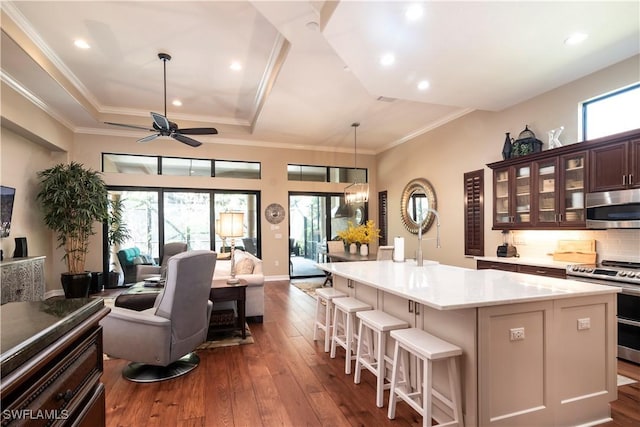 kitchen featuring stainless steel appliances, tasteful backsplash, dark hardwood / wood-style flooring, a kitchen bar, and a kitchen island with sink