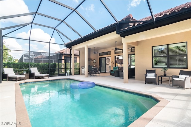 view of pool featuring outdoor lounge area, ceiling fan, a patio area, and glass enclosure